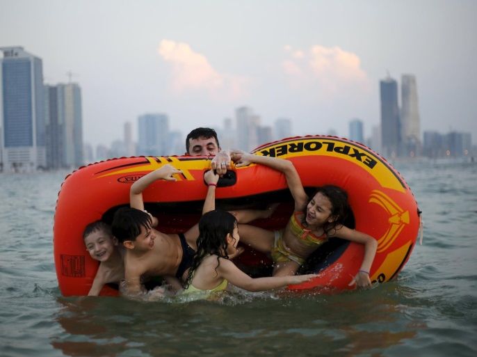 A man plays with his family at Mamzar beach in Dubai, United Arab Emirates in this October 25, 2013 file photo. To match EMIRATES-GOVERNMENT/HAPPINESS REUTERS/Ahmed Jadallah/Files