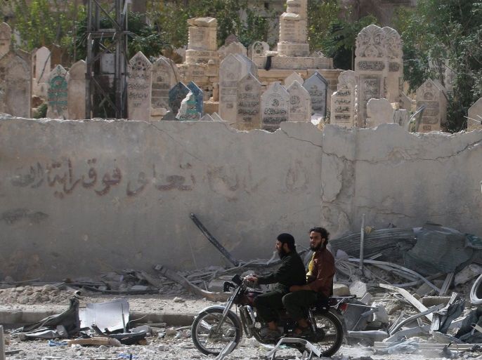 Men drive a motorcycle amidst rubble of damaged buildings near a graveyard after airstrikes on the rebel held al-Qaterji neighbourhood of Aleppo, Syria September 21, 2016. REUTERS/Abdalrhman Ismail