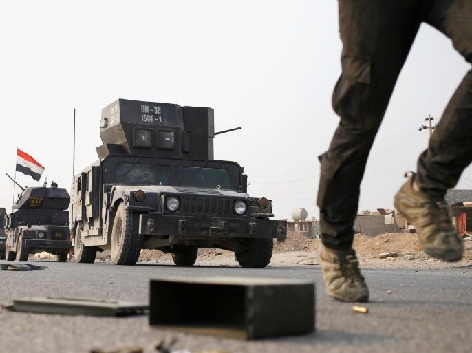 An Iraqi special forces soldier runs as other drive in armoured vehicles on a road near Mosul, Iraq October 25. 2016. REUTERS/Goran Tomasevic TPX IMAGES OF THE DAY