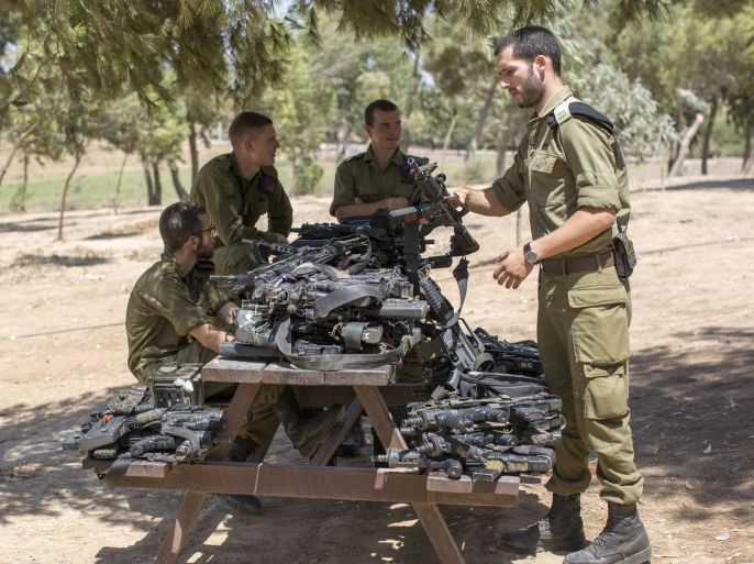 Israeli soldiers have their weapons piled on a table prior to a meeting with Israel's President Reuven Rivlin who came for a visit to the Israeli border with Gaza, in the area named 'Black Arrow', on 23 August 2016. Rivlin reportedly paid the visit to Israeli forces at the border with Gaza after the recent military escalations and to meet with soldiers from a Bedouin Tracker Unit, combat engineers, and members of the 'Givati Brigade' at theso-called 'Black Arrow'
