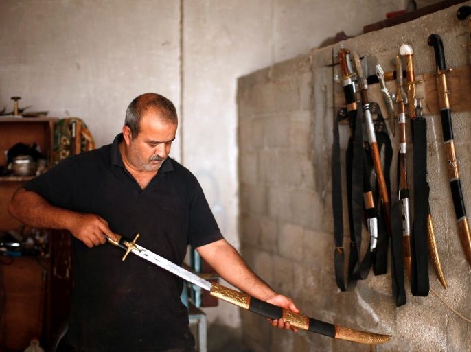 Palestinian blacksmith Mueen Abu Wadi, 45, who inherited the job from his father and grandfather, pulls a sword he made from its holster at his workshop in Gaza City November 14, 2016. REUTERS/Suhaib Salem