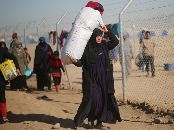 A displaced Iraqi woman, who fled the Islamic State stronghold of Mosul, carries her belongings at Khazer camp, Iraq November 26, 2016. Picture taken November 26, 2016. REUTERS/Mohammed Salem