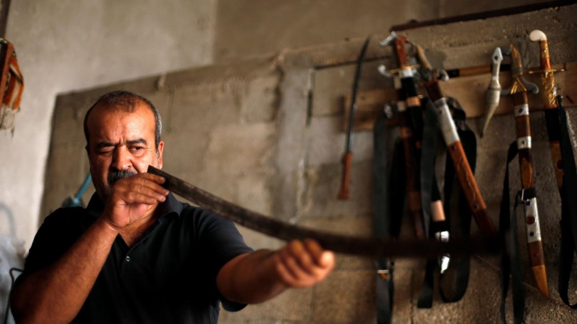 Palestinian blacksmith Mueen Abu Wadi, 45, checks the straightness of a sword in the process of making it at his workshop in Gaza City, as part of a job he inherited from his father and grandfather, November 14, 2016. REUTERS/Suhaib Salem