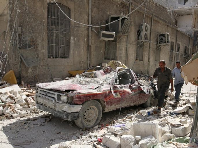 People walk near a damaged vehicle after an air strike Sunday in the rebel-held besieged al-Qaterji neighbourhood of Aleppo, Syria October 17, 2016. REUTERS/Abdalrhman Ismail