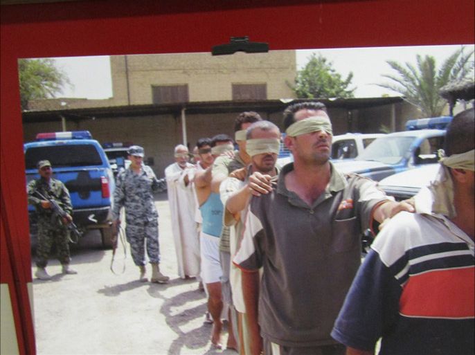 صورة من المعرض لرجال أمن يقتادون مجموعة من المعتقلين وهم معصوبي الأعين.jpg