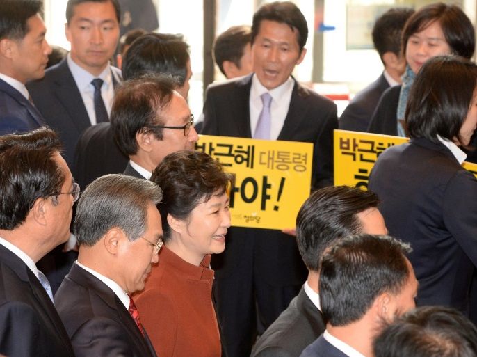 South Korean President Prak Geun-hye (in red) walks past members of the minor opposition Justice Party at the National Assembly in Seoul, South Korea, November 8, 2016. The placards read: "Step down President Park Geun-hye". Yonhap/Bae Jae-man/via REUTERS ATTENTION EDITORS - THIS IMAGE HAS BEEN SUPPLIED BY A THIRD PARTY. SOUTH KOREA OUT. FOR EDITORIAL USE ONLY. NO RESALES. NO ARCHIVE.