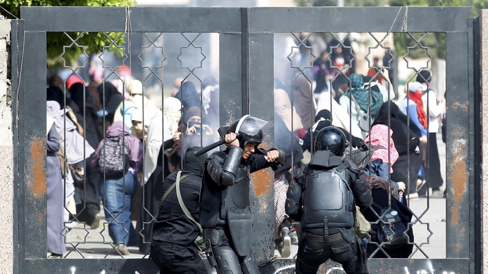 ‪شرطة مكافحة الشغب تحاول خلع بوابة حرم جامعة الأزهر أثناء تظاهرة للطالبات من أنصار الرئيس محمد مرسي‬ (رويترز)