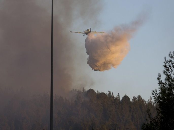 A small plane drops flame retardant on a forest fire burning above the main Route 1 Tel Aviv to Jerusalem highway outside the town of Latroun, Israel on 24 November 2016. Fires have been burning out of control in many places in Israel, but especially in Haifa, northern Israel, where many thousands of residents were evacuated, including hospital patients and university students.