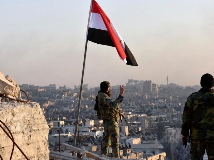 A Syrian government soldier gestures under the Syrian national flag near a general view of eastern Aleppo after they took control of al-Sakhour neigbourhood in Aleppo, Syria in this handout picture provided by SANA on November 28, 2016. To match INSIGHT MIDEAST-CRISIS/SYRIA-ALEPPO-FALL SANA/Handout via REUTERS/File Photo ATTENTION EDITORS - THIS IMAGE WAS PROVIDED BY A THIRD PARTY. EDITORIAL USE ONLY. REUTERS IS UNABLE TO INDEPENDENTLY VERIFY THIS IMAGE.
