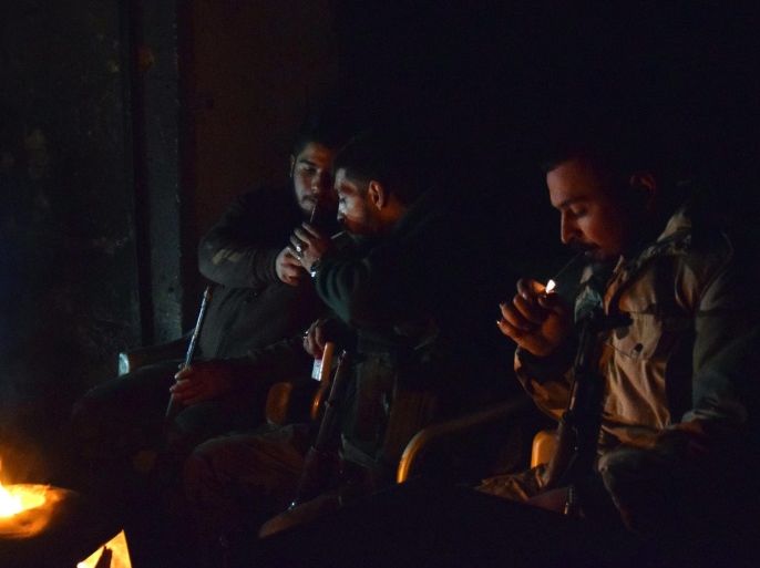 Syrian troops light cigarettes as they sit around a fire in Aleppo, Syria, 29 December 2016. Russian President Putin earlier the day announced that a ceasefire deal had been agreed between the Syrian government and rebel groups which is schedueled to begin at midnight, 30 December 2016.