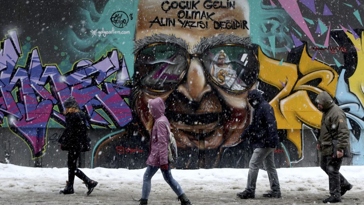 People walk in front of a graffiti reading 'It is not destiny to be a child bride' on Istiklal Street on a snowy day in Istanbul, Turkey, 07 January 2017. Temperatures in Istanbul dropped to minus five degrees Celsius with snow showers.