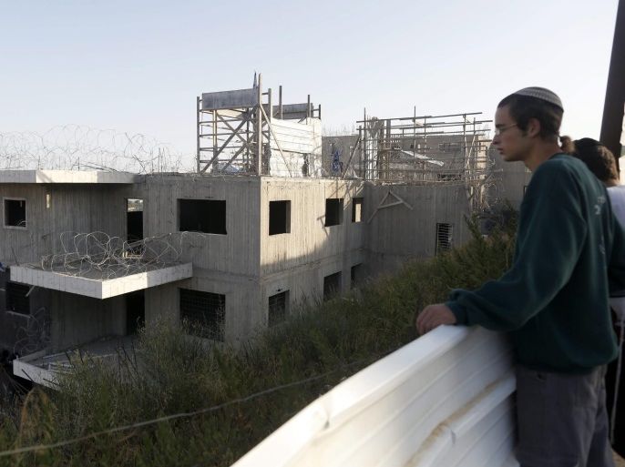 Israeli settlers looki at a 24 housing units illegal building after some dozens militant settlers had barricaded themselves inside overnight prior to an evacuation by Israeli security forces, at the Jewish settlement of Beit El, near the West Bank town of Ramallah, early 28 July 2015. Israel's Supreme Court earlier had ruled to demolish the 24 housing units in the settlement claiming they were illegally built on private Palestinian land.