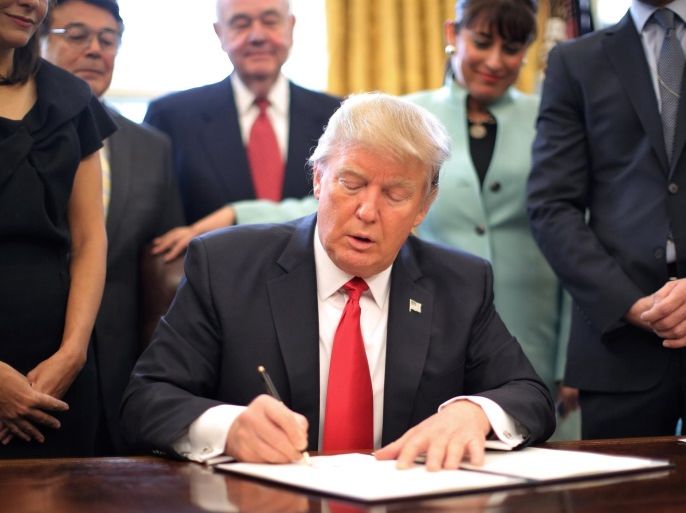 U.S. President Donald Trump signs an executive order cutting regulations, accompanied by small business leaders at the Oval Office of the White House in Washington U.S., January 30, 2017. REUTERS/Carlos Barria