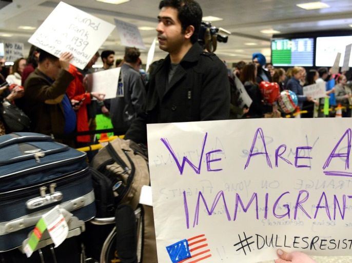 Dozens of pro-immigration demonstrators cheer and hold signs as international passengers arrive at Dulles International Airport, to protest President Donald Trump's travel ban to the United States, in Chantilly, Virginia, in suburban Washington, U.S., January 29, 2017. REUTERS/Mike Theiler