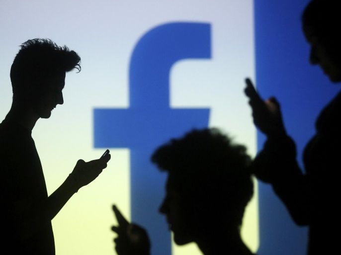 People are silhouetted as they pose with mobile devices in front of a screen projected with a Facebook logo, in this picture illustration taken in Zenica October 29, 2014. Facebook Inc warned on Tuesday of a dramatic increase in spending in 2015 and projected a slowdown in revenue growth this quarter, slicing a tenth off its market value. Facebook shares fell 7.7 percent in premarket trading the day after the social network announced an increase in spending in 2015 and