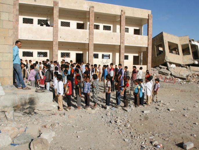 طلاب يقفون في طابور صباحي بإحدى المدارس المهدمة في تعز (رويترز)
