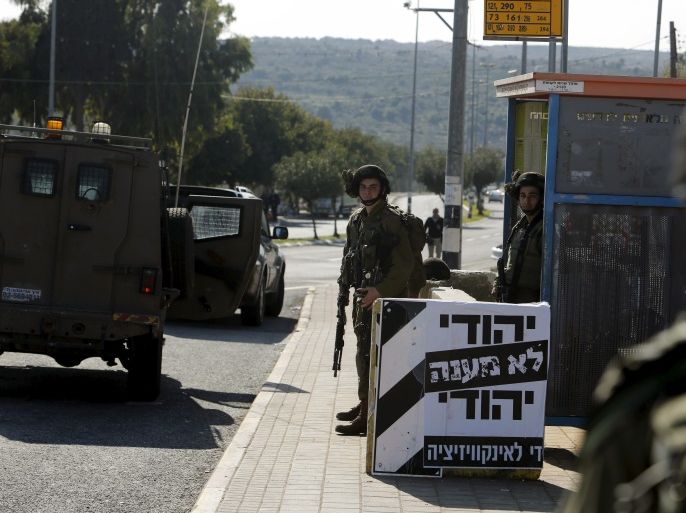 Israeli soldiers stand guard next to a poster which reads in Hebrew