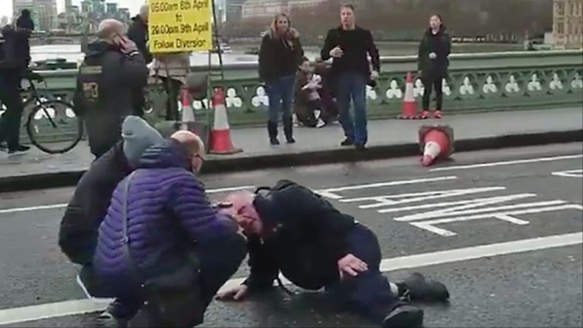 epa05863659 A video grabbed still image, made available by former Polish foreign minister Radoslav Sikorski, showing people attending to an injured person at the Westminster Bridge, near the Houses of Parliament in central London, Britain 22 March 2017. Scotland Yard said on 22 March 21017 the police were called to a firearms incident in the Westminster palace grounds and on Westminster Bridge amid reports of several people injured in central London. EPA/RADOSLAV SIKORS