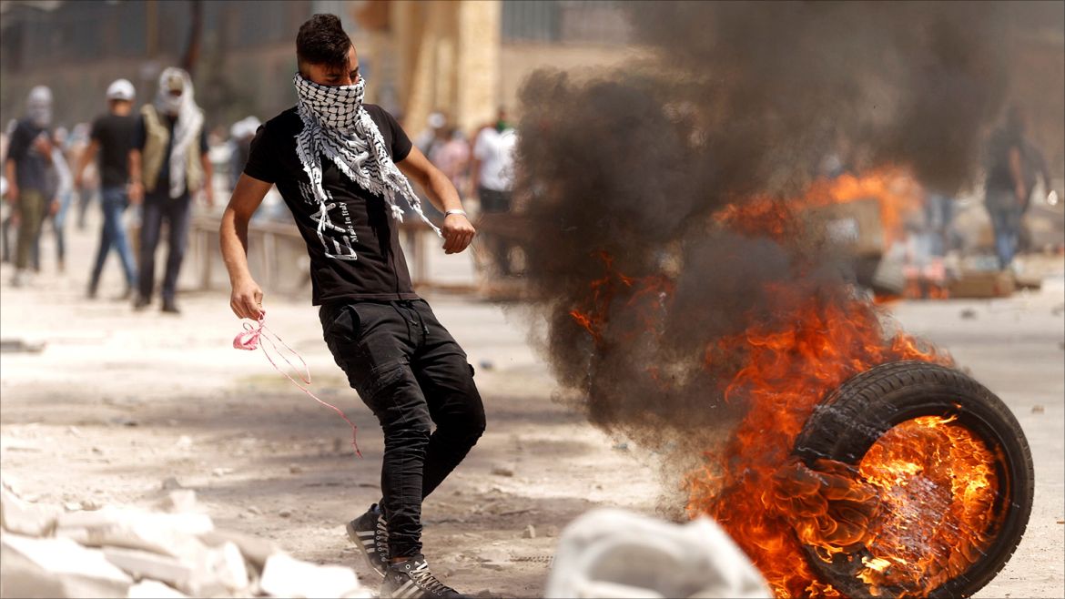 A Palestinian protester moves a burning tyre during clashes with Israeli troops at a protest in support of Palestinian prisoners on hunger strike in Israeli jails, in the West Bank village of Beita, near Nablus April 28, 2017. REUTERS/Mohamad Torokman