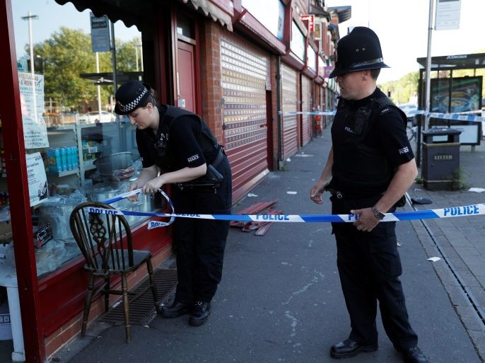 Police officers tie up cordon tape outside a barber's shop in Moss Side which was raided by officers in Manchester, Britain, May 26, 2017. REUTERS/Darren Staples