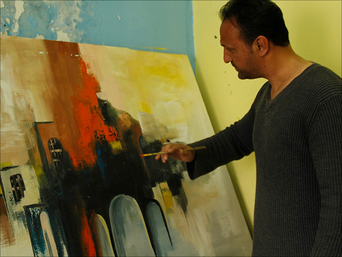 الفنان محمد الشريف يضع اللمسات الأخيرة على إحدى لوحاته(الجزيرة)