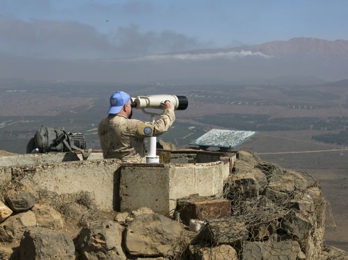 A Canadian member of the United Nations Disengagement Observer Force (UNDOF) looks through binoculars at Mount Bental, an observation post in the Israeli occupied Golan Heights near the ceasefire line between Israel and Syria August 21, 2015. Israel said it killed four Palestinian militants in an air strike on the Syrian Golan Heights on Friday, after cross-border rocket fire from Syria prompted the heaviest Israeli bombardment since the start of Syria's four-year-old civil war. REUTERS/Baz Ratner