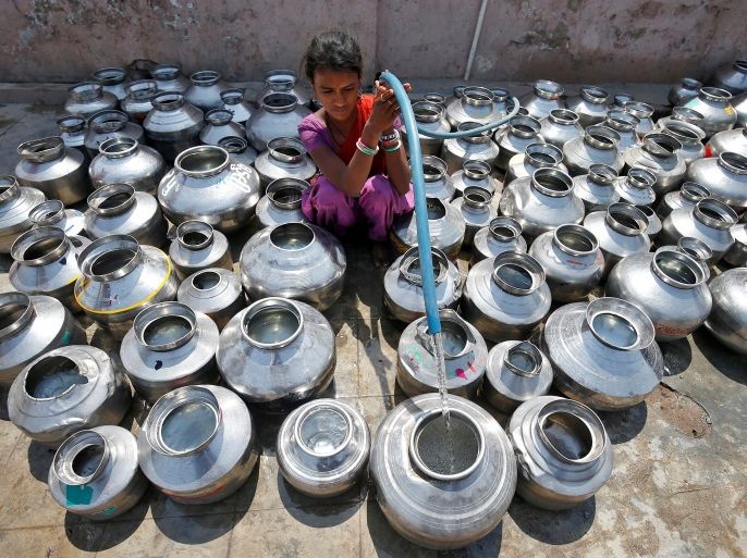 A girl fills metal pitchers with drinking water from a tubewell outside a temple in Ahmedabad, India March 30, 2017. REUTERS/Amit Dave