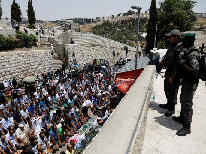 Israeli border police officers stand guard as Palestinians pray at Lions' Gate, the entrance to Jerusalem's Old City, in protest over Israel's new security measures at the compound housing al-Aqsa mosque, known to Muslims as Noble Sanctuary and to Jews as Temple Mount July 20, 2017. REUTERS/Ronen Zvulun