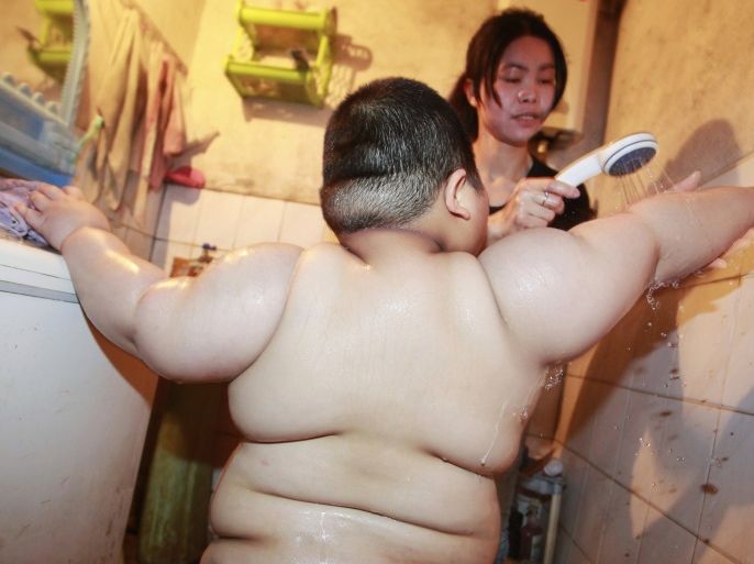 Lu Zhihao, 4, takes a shower with the help of his mother at his house in Foshan, Guangdong province March 28, 2011. Lu, who is 1.1m tall and weighs 62 kg, put on weight dramatically since his appetite grew when he was 3 months old. His worried parents took him to several hospitals, but the reason for his obesity remains unknown, though it is possibly due to his dietary habit, according to local media. Picture taken March 28, 2011. Picture taken March 28, 2011. REUTERS/Joe Tan (CHINA - Tags: SOCIETY HEALTH ODDLY)