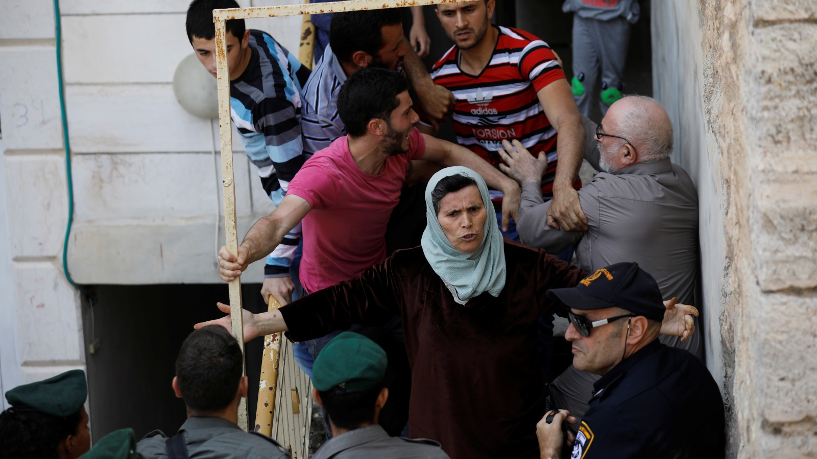 أفراد العائلة الفلسطينية يحاولون منع عناصر أمن الاحتلال من دخول المنزل (رويترز)