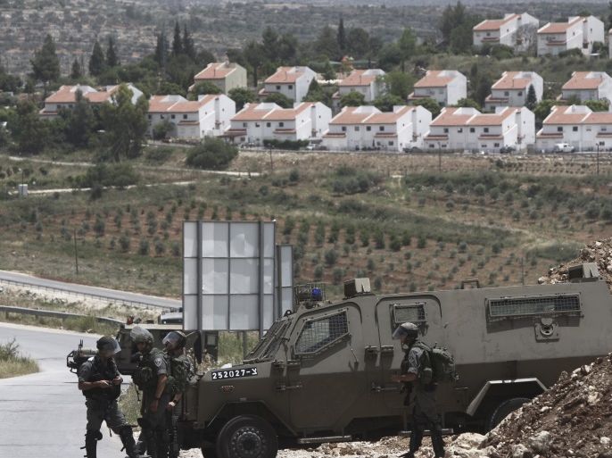 Israeli soldiers guarding the road at the Palestinian village of Nabi Saleh, West Bank, and the Jewish settlement of Halamish