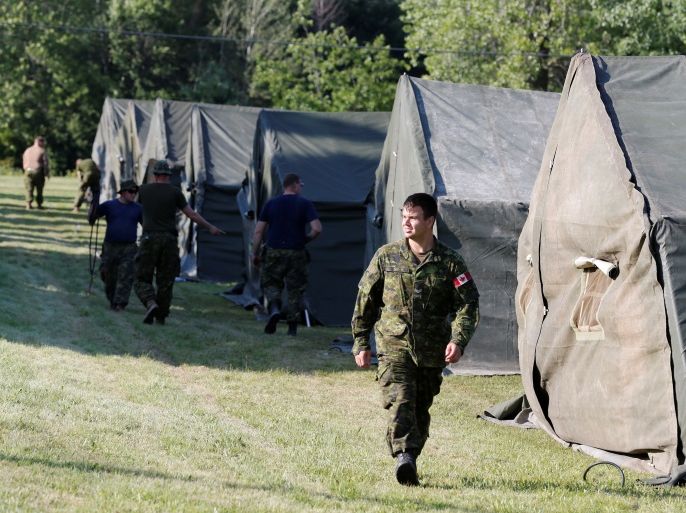 Members of the Canadian Armed Forces walk past tents they erected to house asylum seekers at the Canada-United States border in Lacolle, Quebec, August 9, 2017. REUTERS/Christinne Muschi