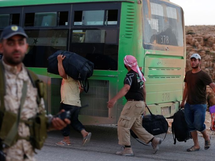 Syrian men carry their bags near a bus in Jroud Arsal, Lebanon August 2, 2017. REUTERS/ Mohamed Azakir