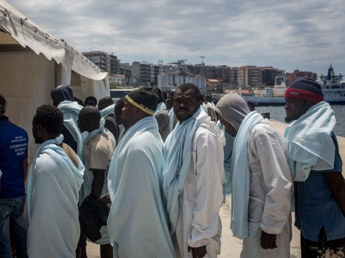 REGGIO CALABRIA, ITALY - JUNE 12: Refugees and migrants wait to be processed after disembarking the Migrant Offshore Aid Station (MOAS) Phoenix vessel at port on June 12, 2017 in Reggio Calabria, Italy. An estimated 230,000 refugees and migrants will arrive in Italy this year as numbers of refugees and migrants attempting the dangerous central mediterranean crossing from Libya to Italy continues to rise since the same time last year. So far this year more than 58,000 p