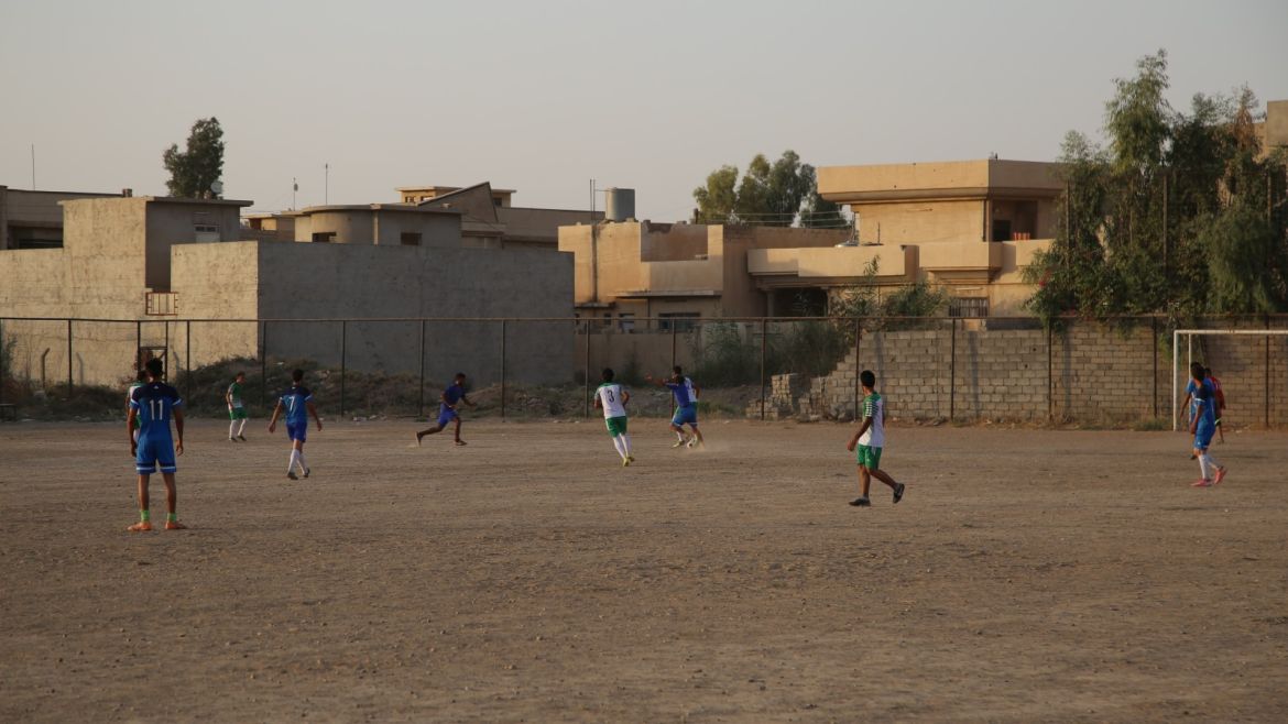شباب من الموصل يلعبون كرة القدم بأحد الملاعب الشعبية