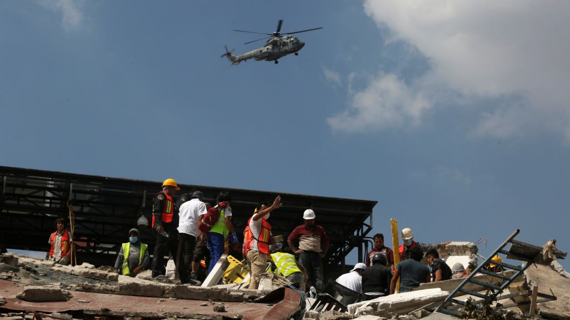 A military helicopter flies over a collapsed building as rescue personnel look for people among the rubble after an earthquake hit Mexico City, Mexico September 19, 2017. REUTERS/Claudia Daut