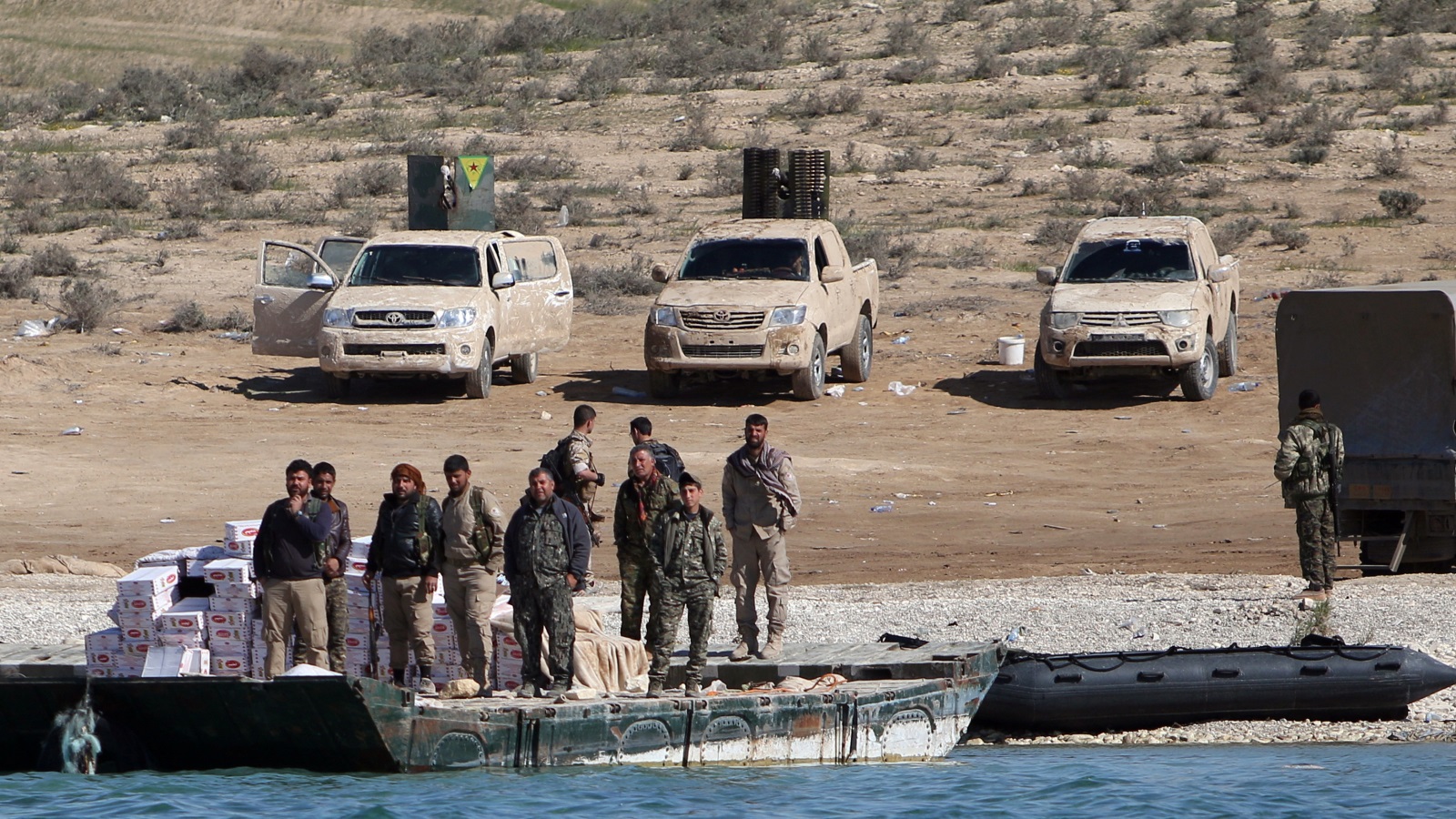أفراد من قوات سوريا الديمقراطية ينشترون قرب ضفة نهر الفرات بسوريا أوائل أبريل/نيسان الماضي (رويترز)