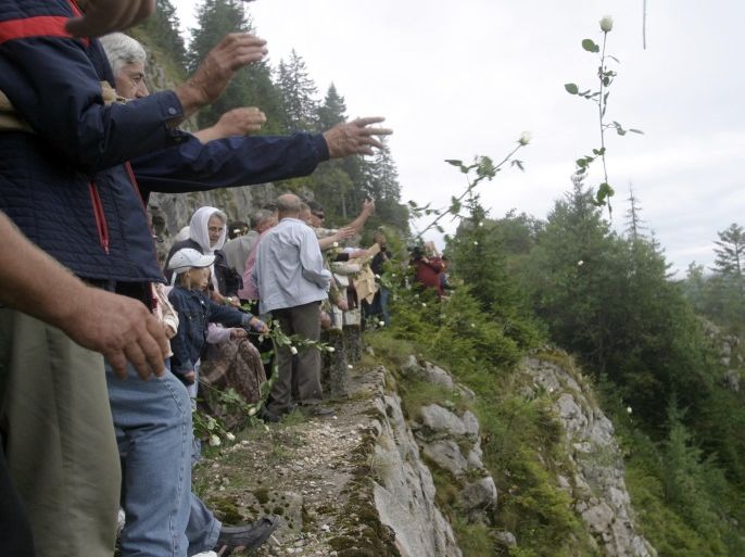 Bosnian Muslims throw flowers from a hill while attending a 14th anniversary commemorating the deaths of Bosnian Muslims, on Vlasic mountain, south of Banja Luka August 21, 2006. Thousands of non-Serbs were tortured and murdered in three notorious camps in western Bosnia in 1992, and several of their high-profile Serb commanders have been sentenced by the U.N. war crimes tribunal in The Hague for the atrocities committed there. REUTERS/Ranko Cukovic (BOSNIA AND HERZEGOVINA)