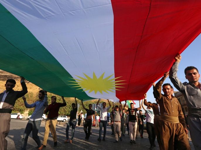 Iraqi Kurds holds a large Kurdish flag as they walk near the citadel towards a gathering urging people to vote in the upcoming independence referendum in Arbil, the capital of the autonomous Kurdish region of northern Iraq, on September 13, 2017. Iraq's autonomous Kurdish region will hold a historic referendum on statehood in September 2017, despite opposition to independence from Baghdad and possibly beyond. / AFP PHOTO / SAFIN HAMED (Photo credit should read S