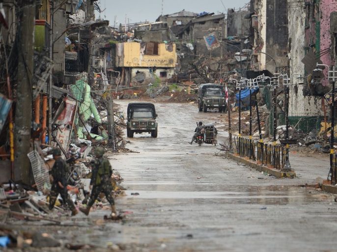 This photo taken on October 17, 2017 shows Philippine soldiers on a street flanked by destroyed buildings in Marawi on the southern island of Mindanao. At first glance, the endless rows of devastated buildings could be the aftermath of a great earthquake. But the punctured, bullet-riddled walls tell the true story of the Philippines' longest urban war. / AFP PHOTO / TED ALJIBE / TO GO WITH AFP STORY PHILIPPINES-UNREST-CONFLICT,FOCUS BY CECIL MORELLA (Photo credi