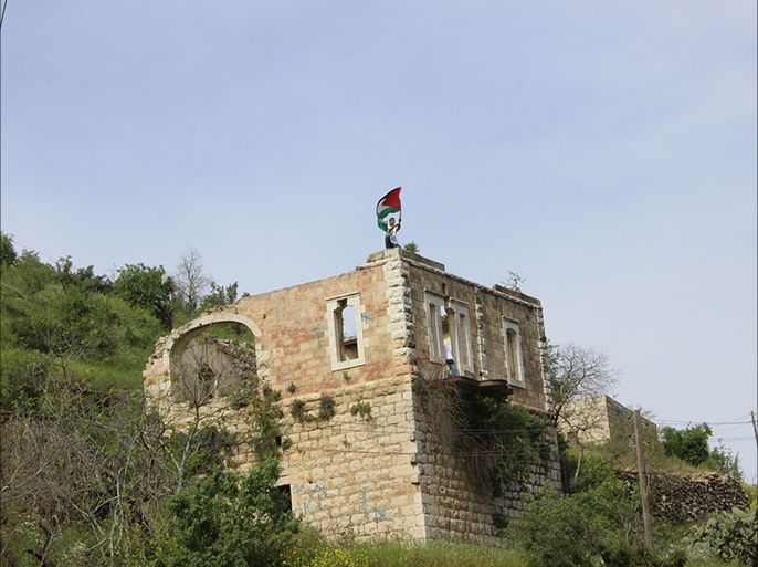 شاب مقدسي يرفع العلم الفلسطيني فوق أحد المنازل المدمرة في قرية لفتا المقدسية المهجرة عام 1948