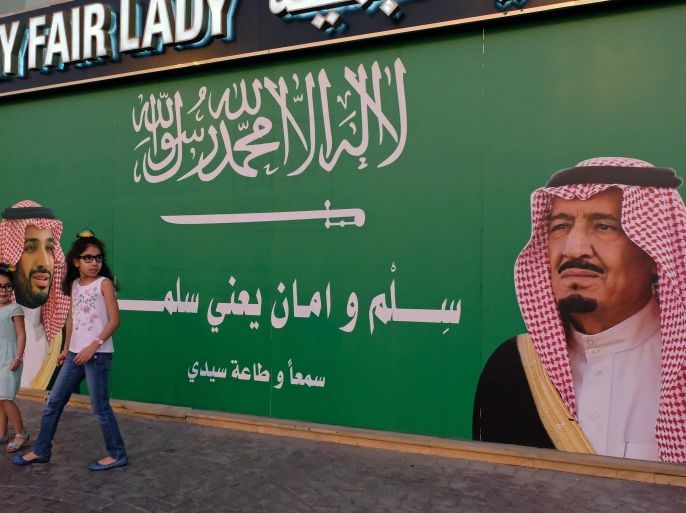 Girls stand next to a poster depicting Saudi Arabia's King Salman bin Abdulaziz Al Saud and Crown Prince Mohammed bin Salman in Jeddah, Saudi Arabia November 10, 2017. REUTERS/Reem Baeshen