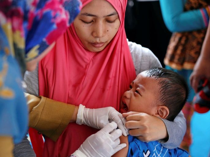 A mother holds her child as he is re-vaccinated by healthcare workers after receiving fake medication from a drug-making ring, at a clinic in East Jakarta, Indonesia, July 18, 2016.REUTERS/Darren Whiteside
