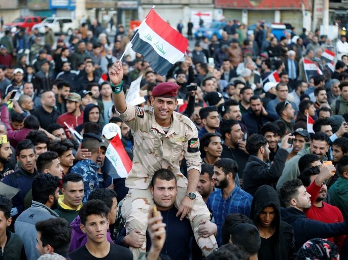A member of Iraqi security forces carries an Iraqi flag as he celebrates the final victory over the Islamic State at Tahrir Square in Baghdad, Iraq December 10, 2017. REUTERS/Thaier Al-Sudani