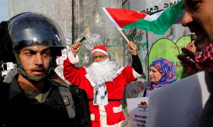 A Palestinian dressed as Santa Claus stands next to an Israeli border police during clashes in the West Bank city of Bethlehem, December 23, 2017. REUTERS/Ammar Awad