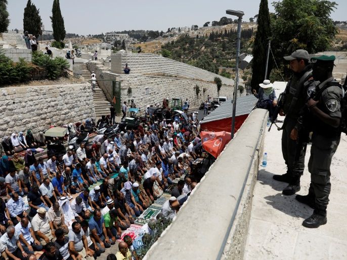 Israeli border police officers stand guard as Palestinians pray at Lions' Gate, the entrance to Jerusalem's Old City, in protest over Israel's new security measures at the compound housing al-Aqsa mosque, known to Muslims as Noble Sanctuary and to Jews as Temple Mount July 20, 2017. REUTERS/Ronen Zvulun