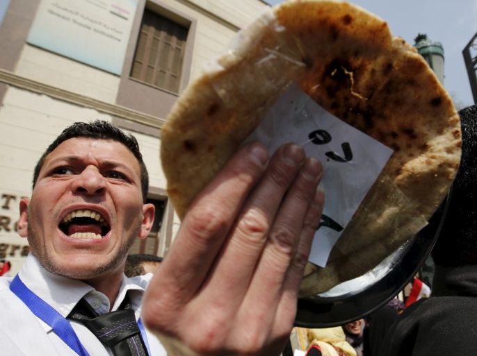 A man gestures with a piece of bread during a protest, to demand the government to offer unemployed graduates jobs, in front of the parliament headquarters in Cairo, March 27, 2016, where Egyptian Prime Minister Sherif Ismail was speaking. REUTERS/Amr Abdallah Dalsh