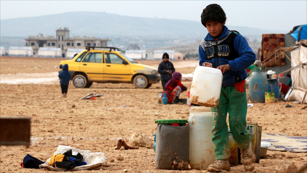 epa06421126 An Internally displaced boy carries a water jerrycan at the Kalbeed makeshift camp, near Bab al-Hawa crossing by the Syrian-Turkish border, 06 January 2018. Hundreds of families fled the fighting between government and opposition forces around Idlib.  EPA-EFE/ZEIN ALRIFAII