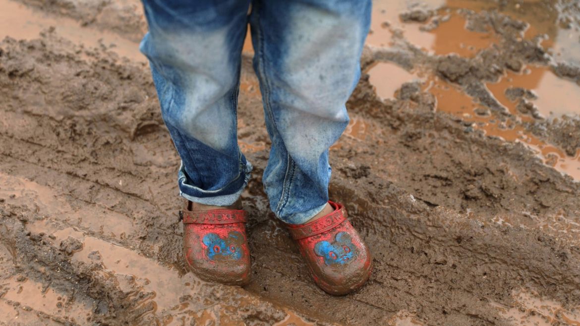 An internally displaced child wearing muddy shoes stands at a refugee camp in Quneitra, Syria, January 19, 2018. REUTERS/Alaa Al-Faqir