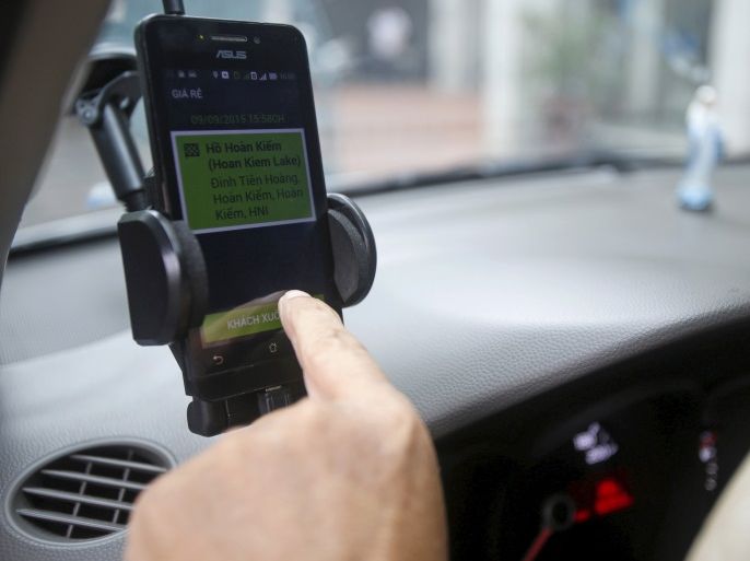 A GrabTaxi touches on his smartphone to check the bill for a customer in Hanoi, Vietnam, September 9, 2015. A young, tech-savvy population short on cars but big on smartphones is driving double-digit growth for ride-hailing apps Uber and GrabTaxi in Vietnam, and inspiring some executives to dream of replacing private car ownership altogether. Ride-sharing apps have taken off among Vietnam's rapidly expanding middle class as they provide four-wheeled comfort in a countr